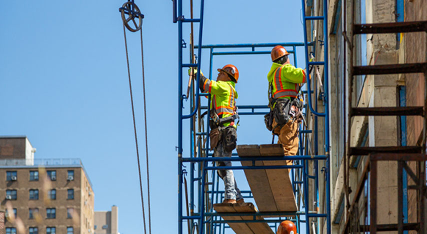 two construction workers standing on scaffolding