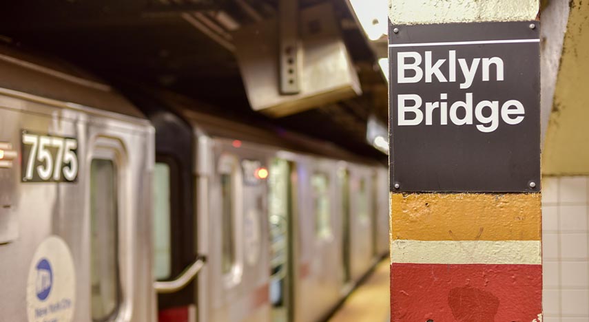Subway cars next to a sign that says "Bklyn Bridge"