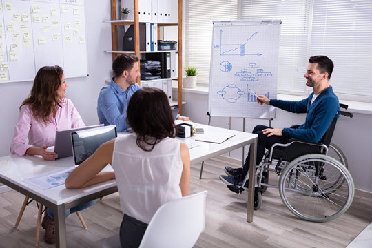 An individual in a wheelchair leading a meeting.