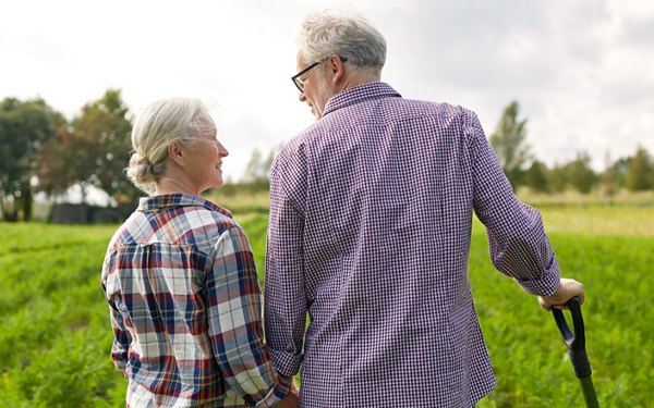 Rural scene of an older male and female holding hands and surveying their farm field.