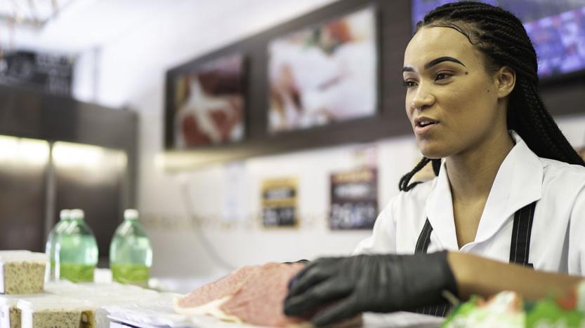 A young employee working at a deli counter.